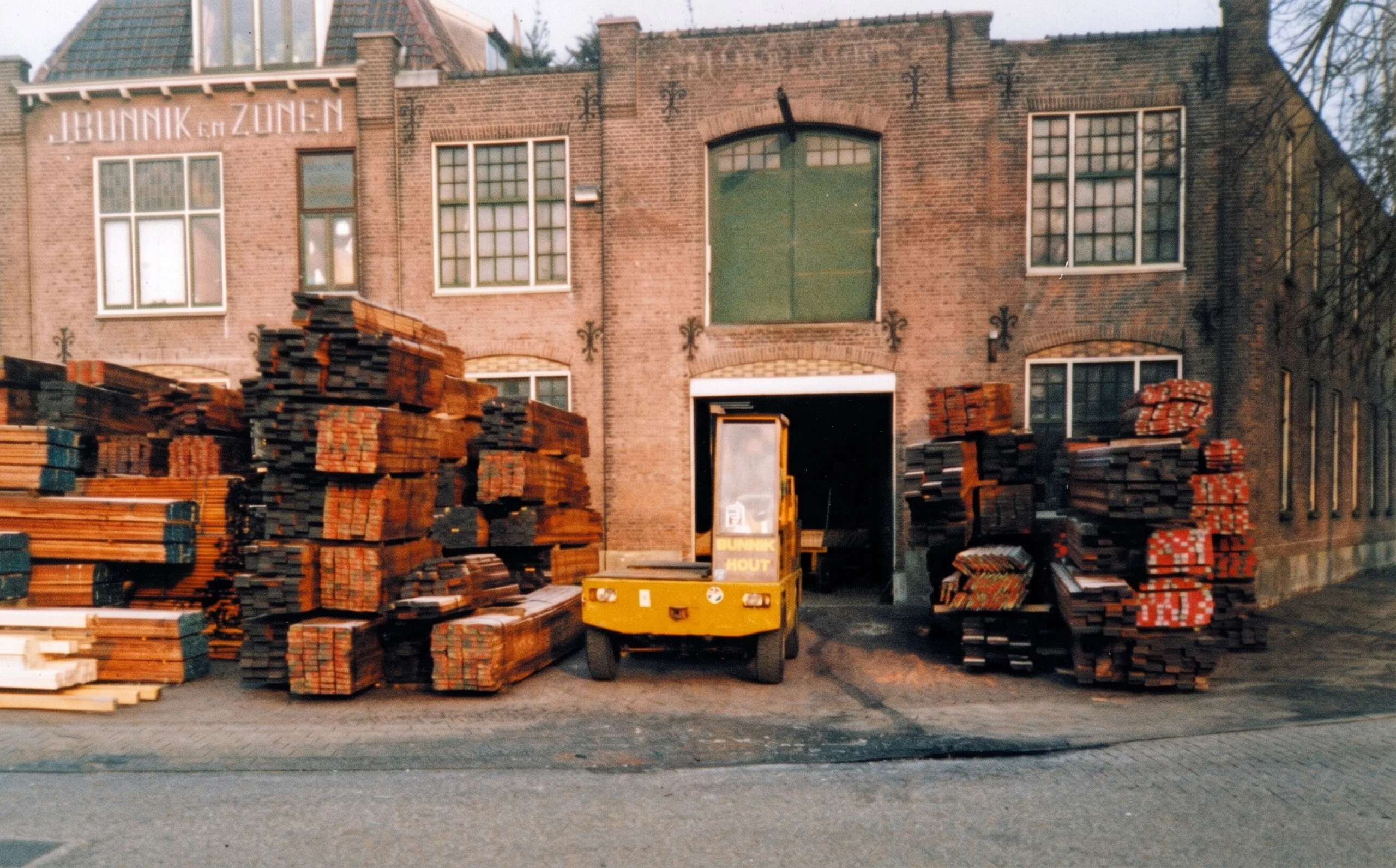 Gestapeld hout voor de fabriek, met een heftruck
