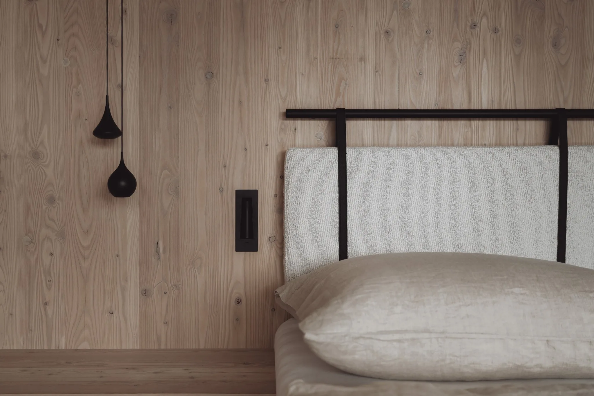 Slaapkamerwand in massief hout met een bed en hanglampen